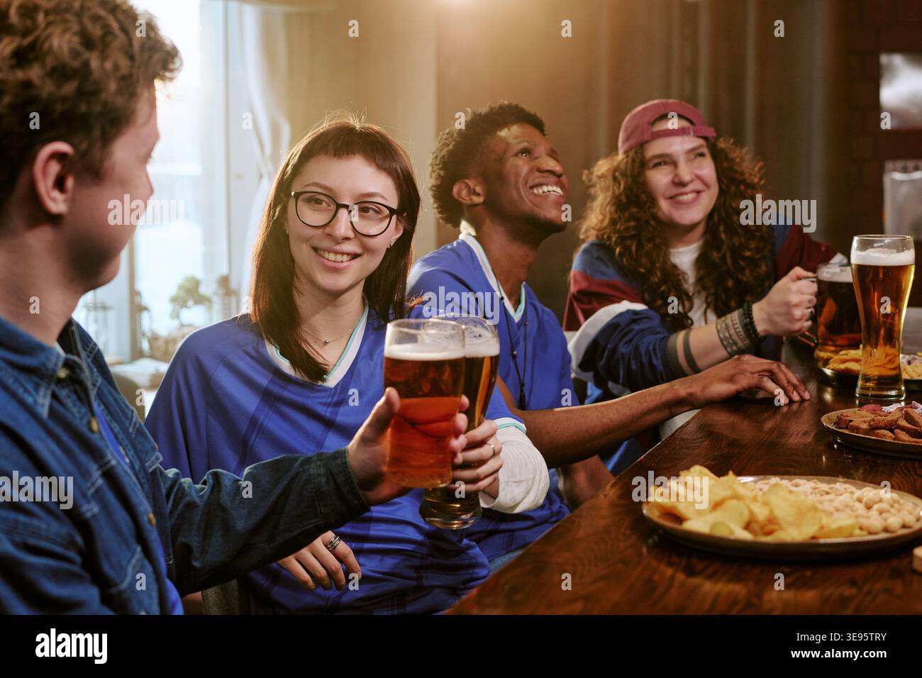 Divers amis buvant de la bière tout en regardant Sports in Pub Banque D'Images