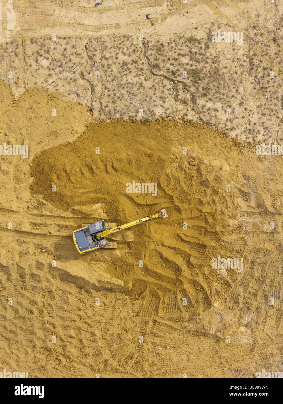 Vue aérienne d'une pelle jaune creusant dans un grand chantier de construction avec un sol brun et des traces de pneus visibles Taiwan. Banque D'Images