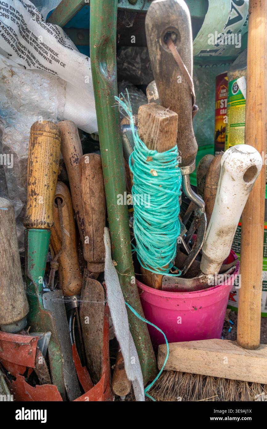 Outils à main de jardinage rangés sur le sol dans un coin d'une serre Banque D'Images