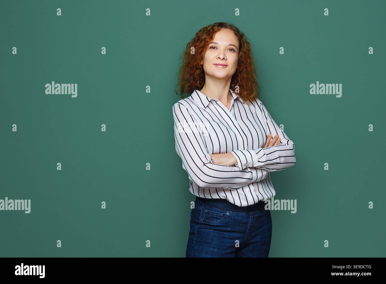 Femme d'affaires souriante posant avec les bras pliés, regardant dans la caméra sur un fond coloré Banque D'Images