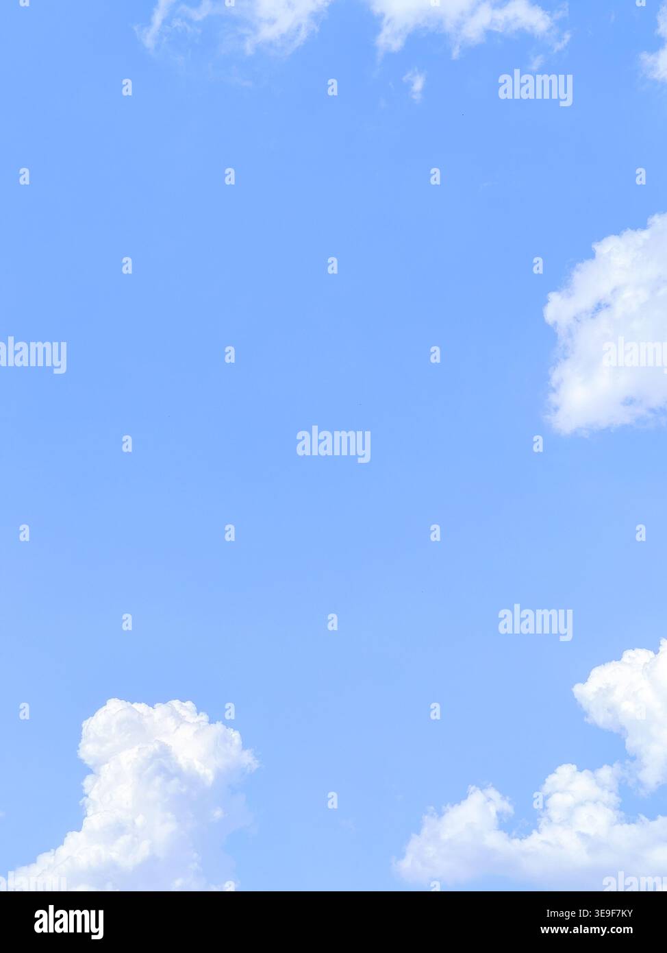 Texture de fond verticale d'un ciel bleu clair lumineux avec des nuages de cumulus blancs moelleux sur une belle journée d'été ensoleillée. Banque D'Images