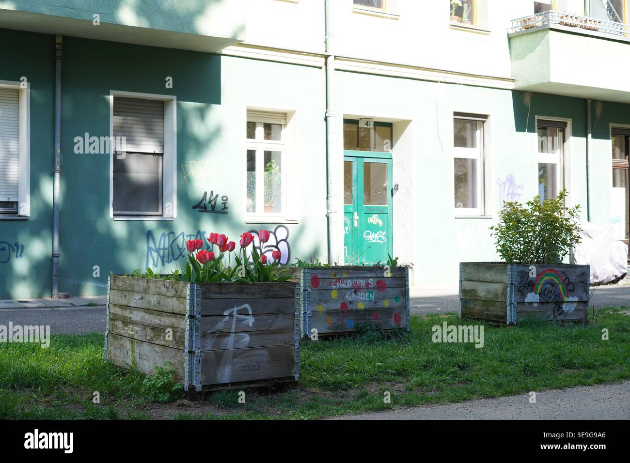 Berlin, Allemagne - 17 avril 2026 : parterres de fleurs en bois surélevés avec des tulipes rouges devant un immeuble résidentiel à Elsenstraße au printemps. Banque D'Images