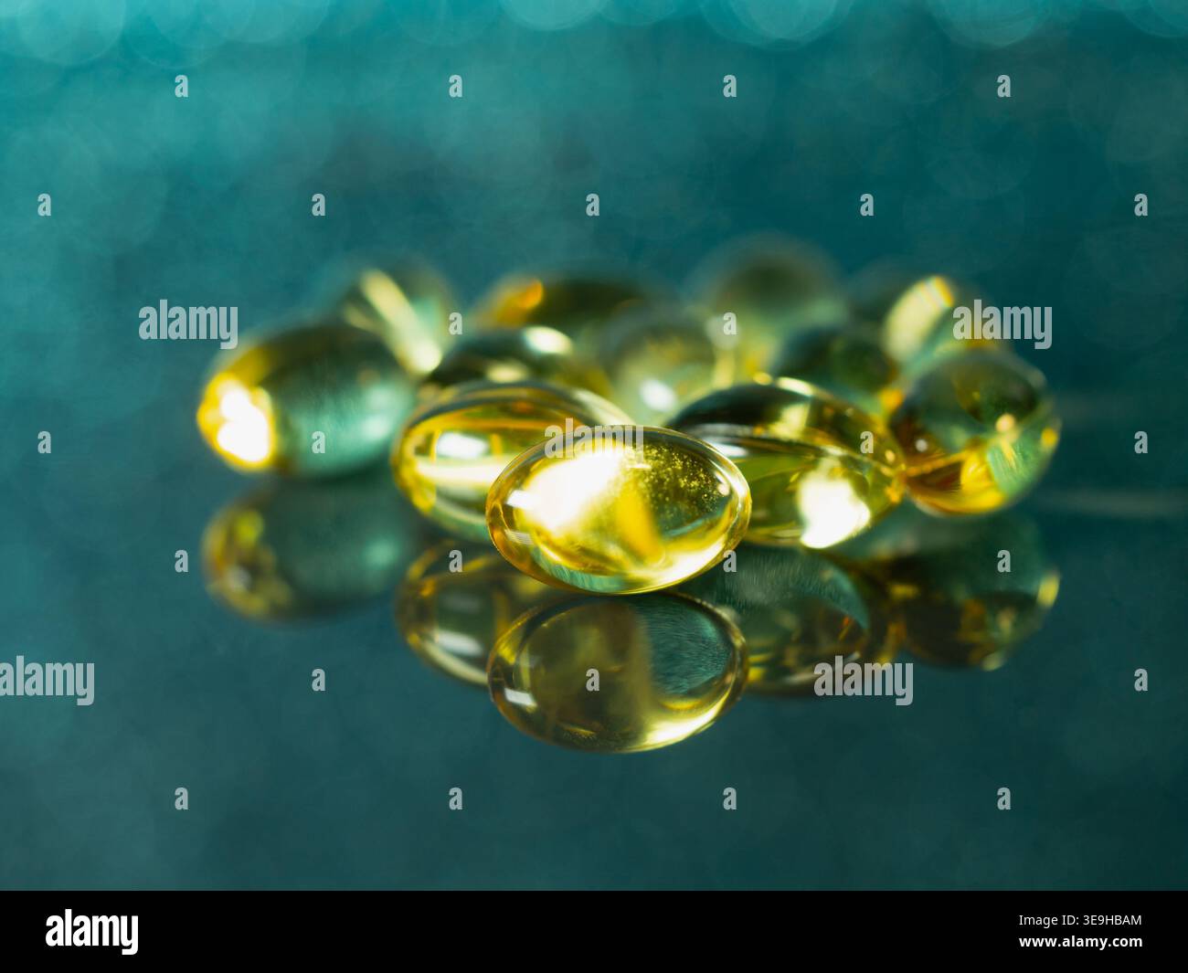 poignée de pilules transparentes d'or avec de l'huile de poisson sur un fond bleu Banque D'Images