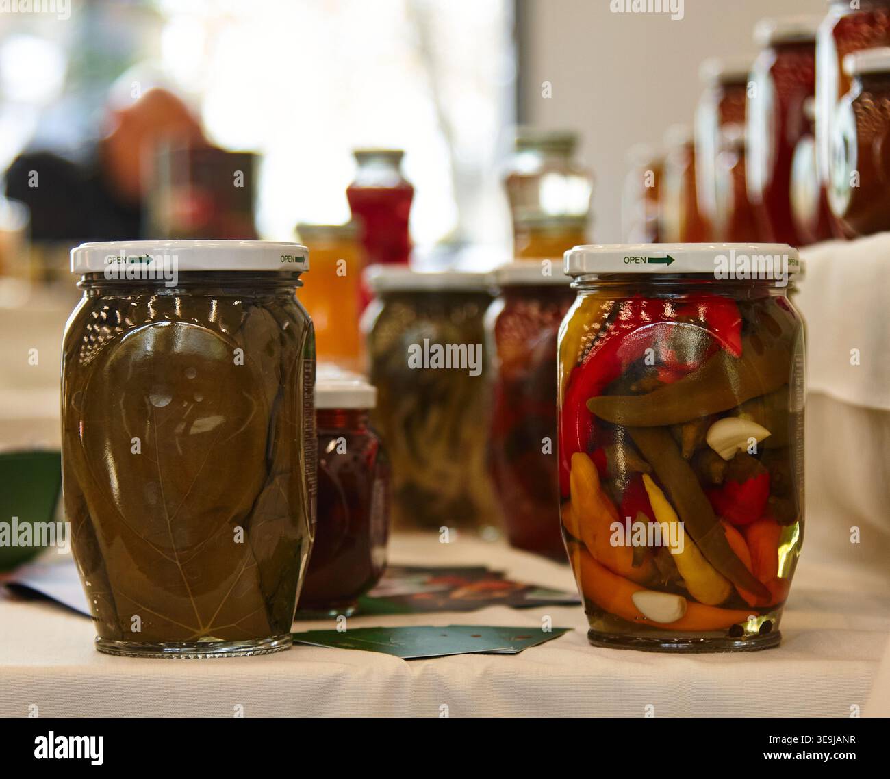 Des bocaux en verre remplis de légumes marinés, dont des poivrons et des concombres, disposés sur une table, présentent des spécialités culinaires arméniennes traditionnelles Banque D'Images
