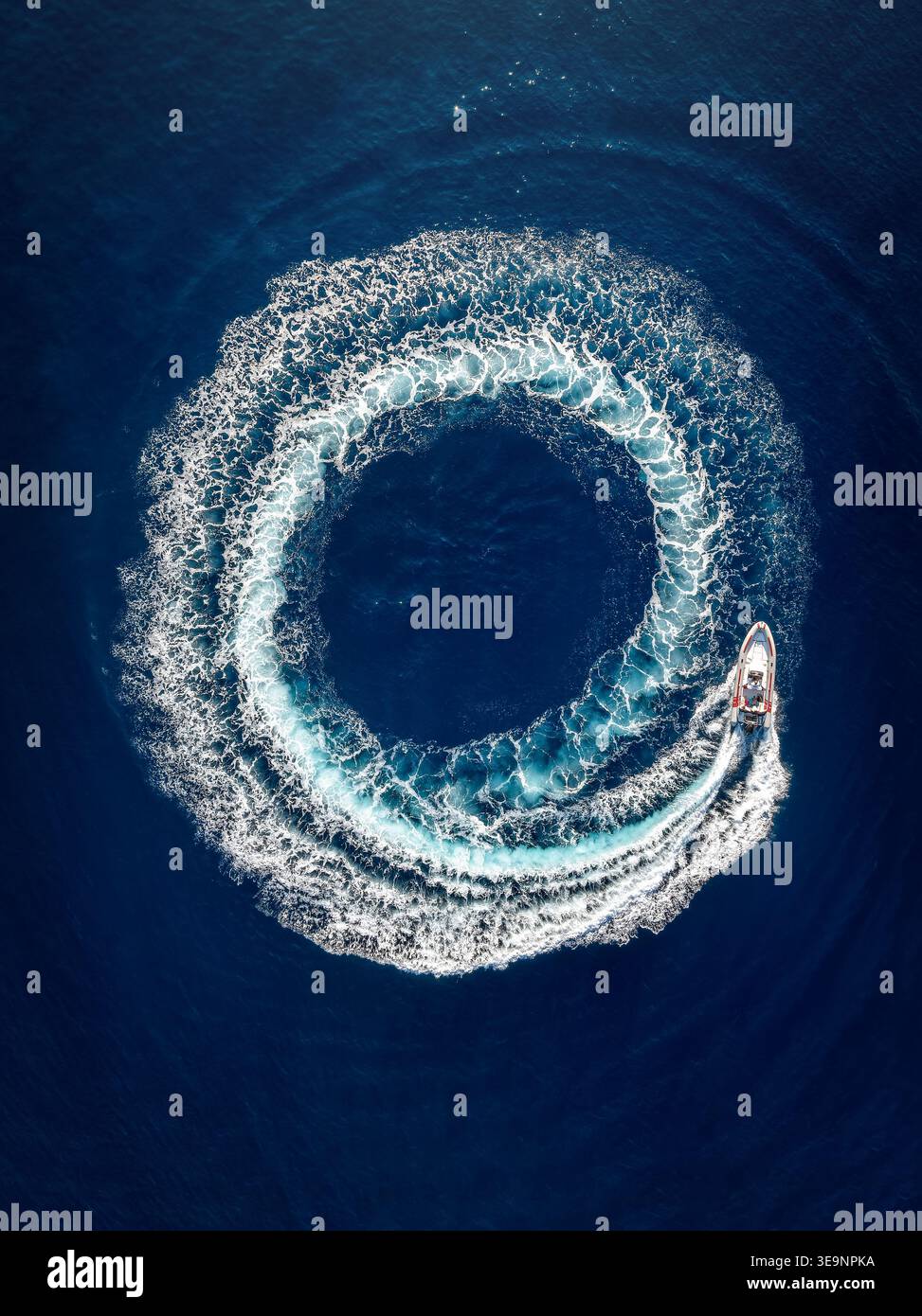 Vue aérienne de dessus d'un bateau RIDEAU À moteur formant un cercle de bulles et surfant avec son moteur au-dessus de l'océan bleu Banque D'Images