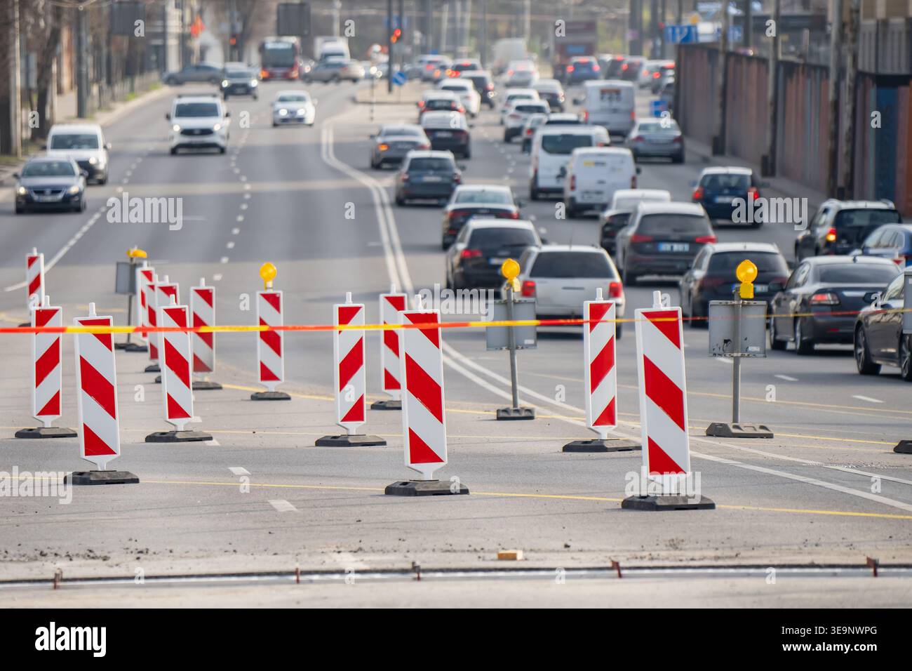 Fermeture temporaire des voies sur les routes urbaines à voies multiples avec barrières d'avertissement rayées, circulation de véhicules lourds et gestion active des réparations de rues Banque D'Images