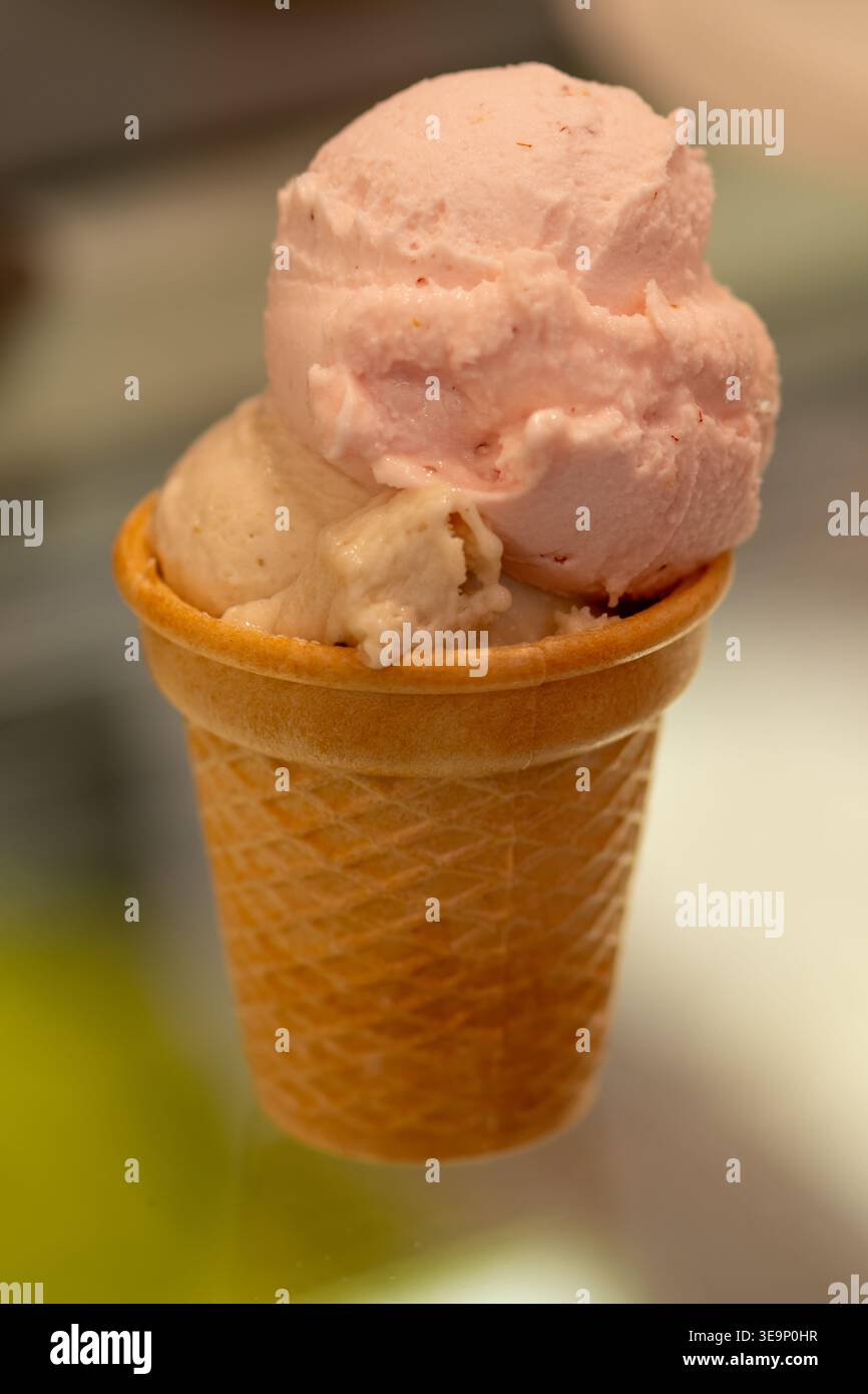 Crème glacée en cornet de gaufre avec deux saveurs servies en gros plan sur fond flou. Banque D'Images