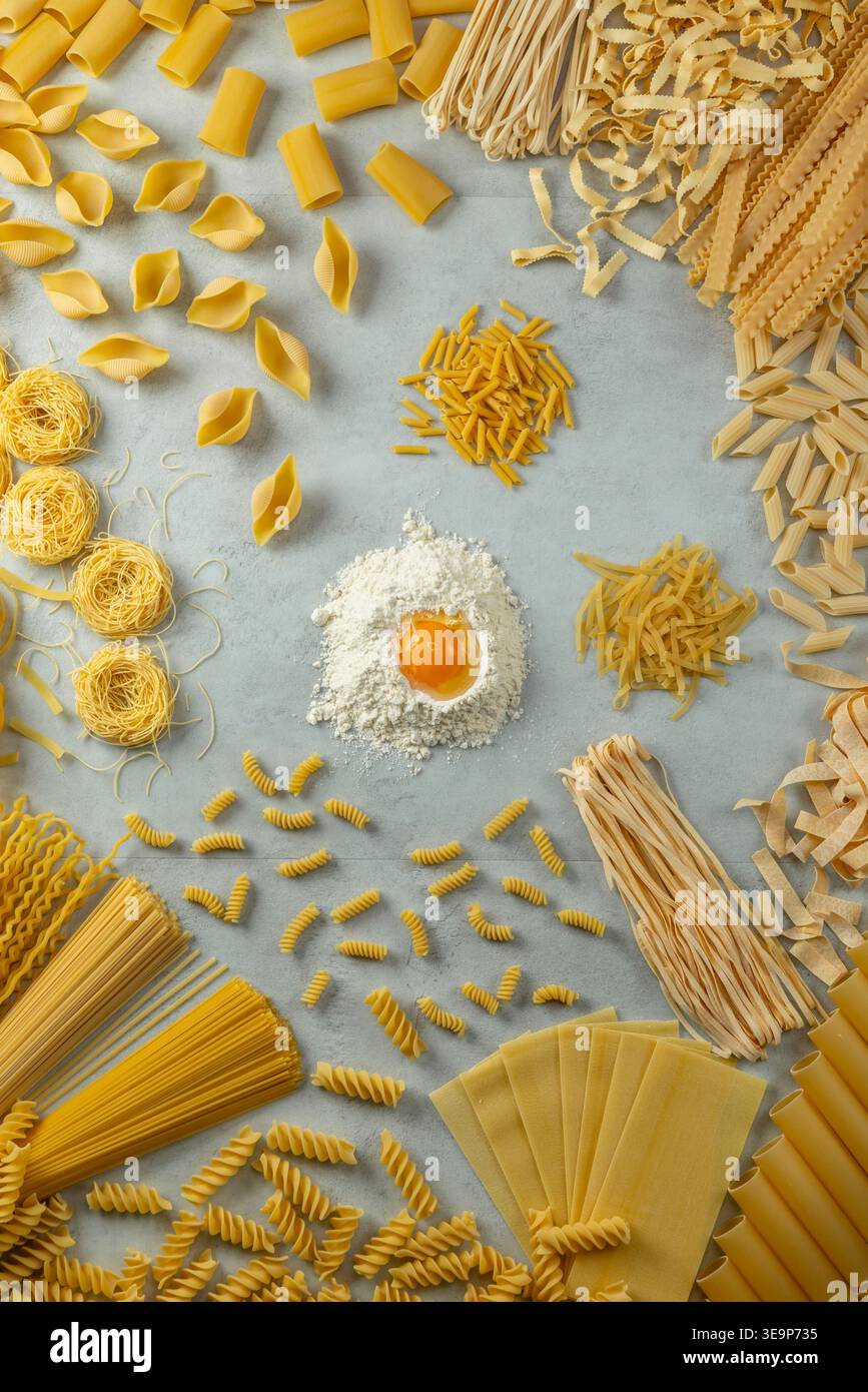 Variété de pâtes non cuites, farine et jaune d'oeuf cru prêt à faire des pâtes fraîches Banque D'Images