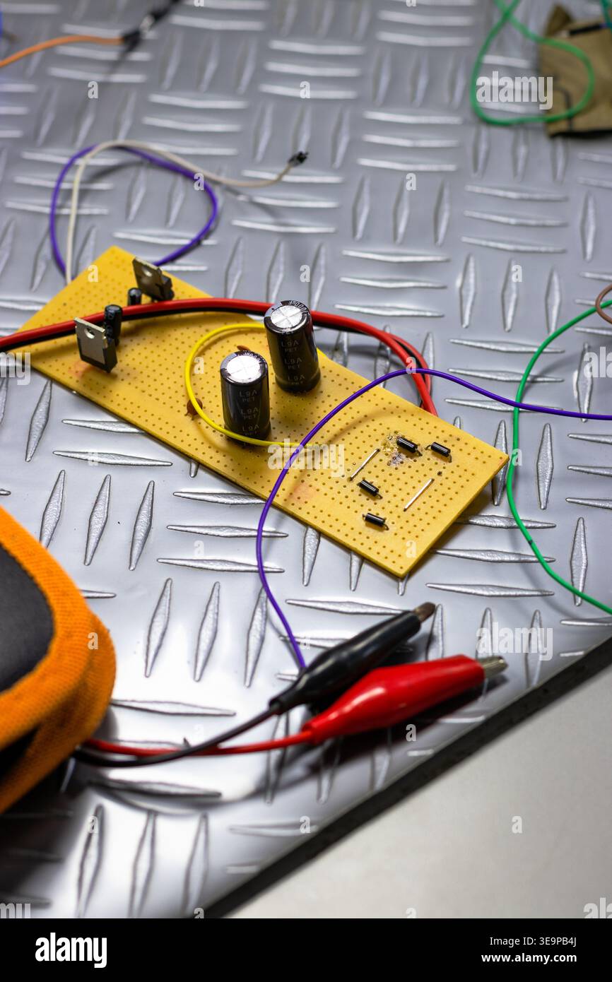 Un tas de fils et de composants électroniques sont sur une surface grise. Les fils sont emmêlés et les composants dispersés. La scène est chaotique et disorga Banque D'Images