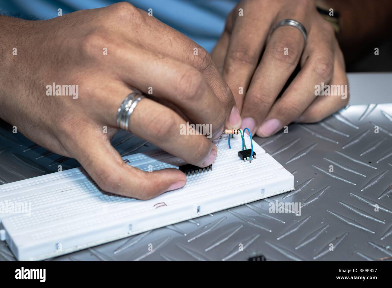 Un homme travaille sur un circuit imprimé avec une montre au poignet. Il est concentré sur la tâche à accomplir et il s'amuse Banque D'Images