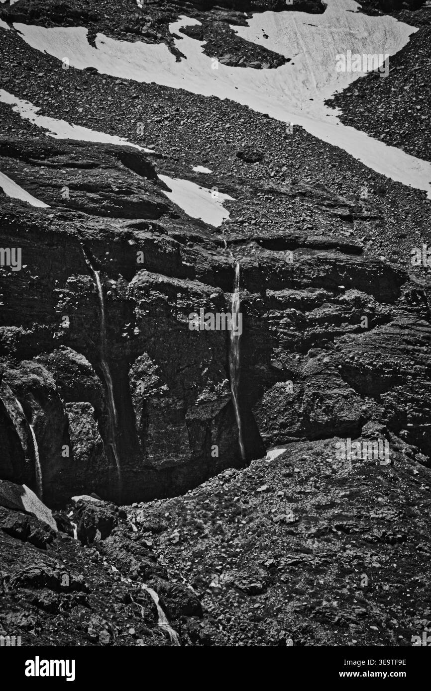Pente de montagne rocheuse avec neige fondante et petite cascade dans Un parc chilien Banque D'Images