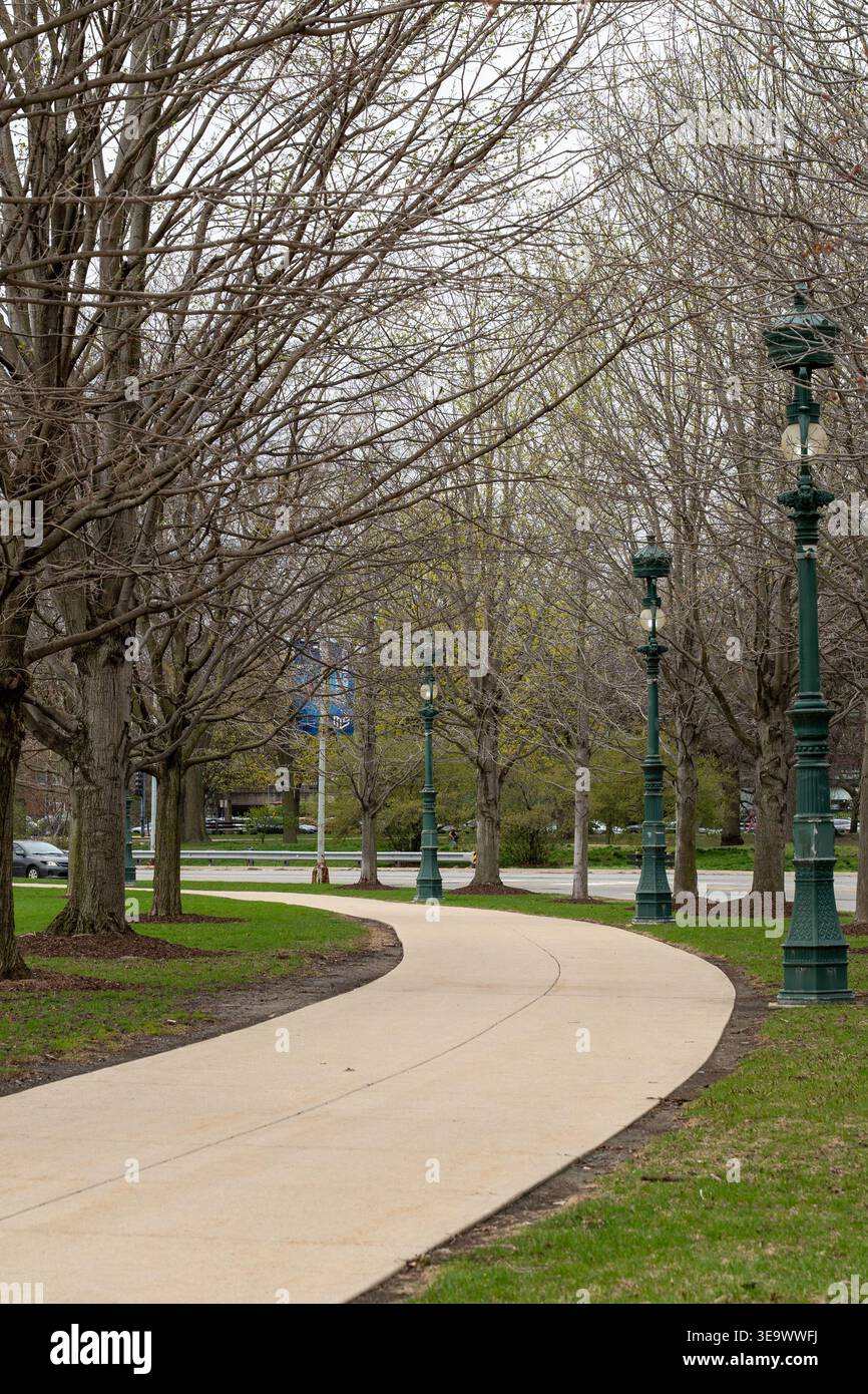 Photo verticale d'un sentier asphalté dans un parc américain, entouré d'arbres et d'herbe luxuriante, invitant à une promenade paisible dans la nature Banque D'Images