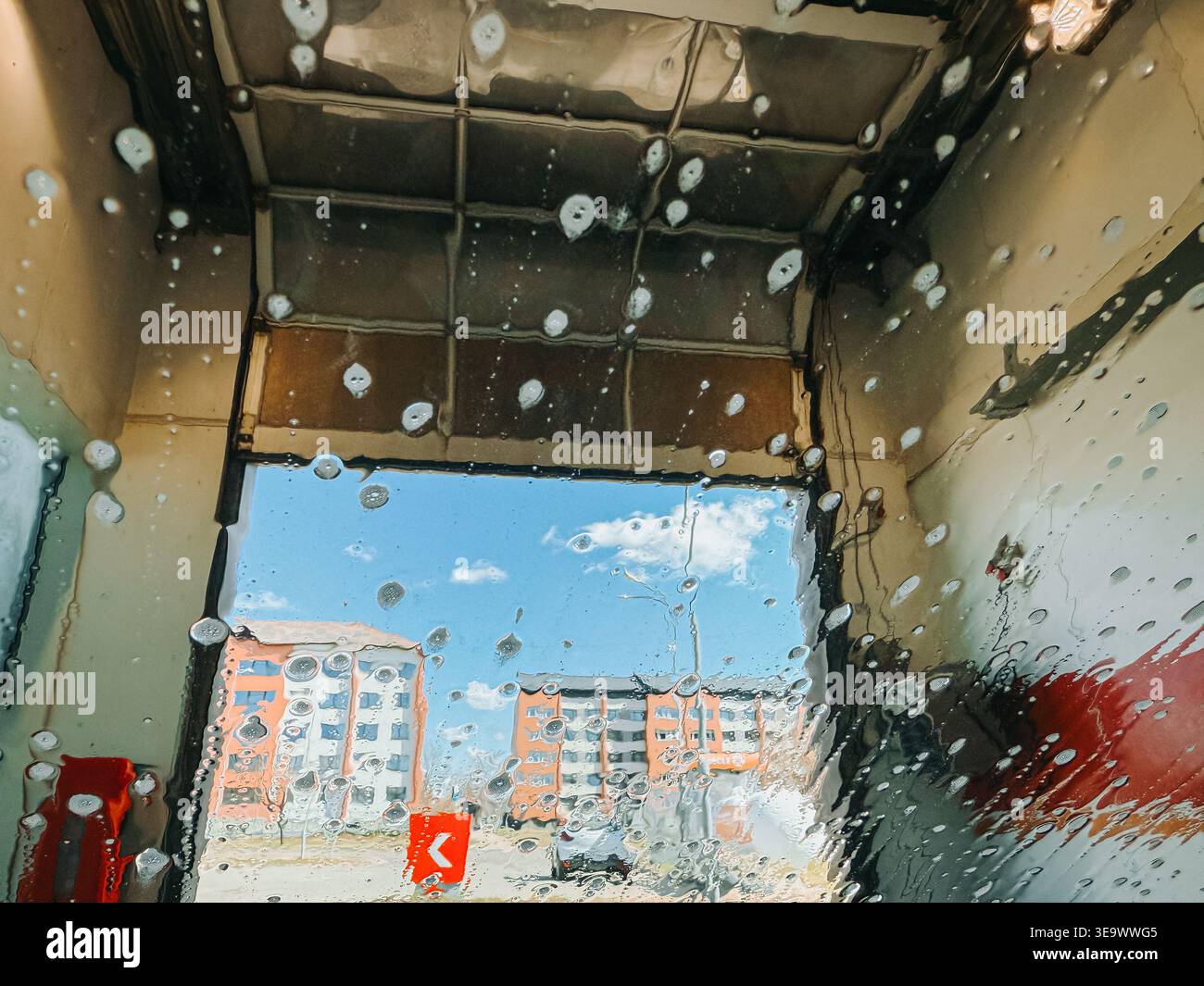 Valmiera, Lettonie - 18 avril 2026:perspective de l'intérieur d'une voiture lors d'un lavage automatique, avec des gouttelettes d'eau et de la mousse sur le pare-brise et floue u Banque D'Images