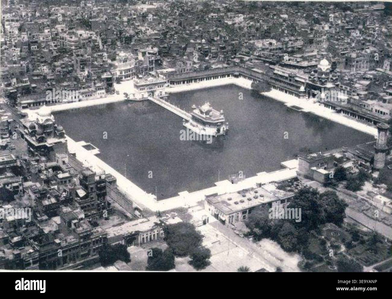 Le Temple d'Or (Harmandir Sahib), situé à Amritsar, au Pendjab, est le site le plus sacré du Sikhisme. Cette vue aérienne capture la grandeur du temple et de son complexe environnant, y compris le Sarovar (réservoir d'eau sacrée). L'image est une photographie d'archives du milieu du XXe siècle, mettant en valeur la beauté architecturale et l'importance culturelle du temple. Banque D'Images