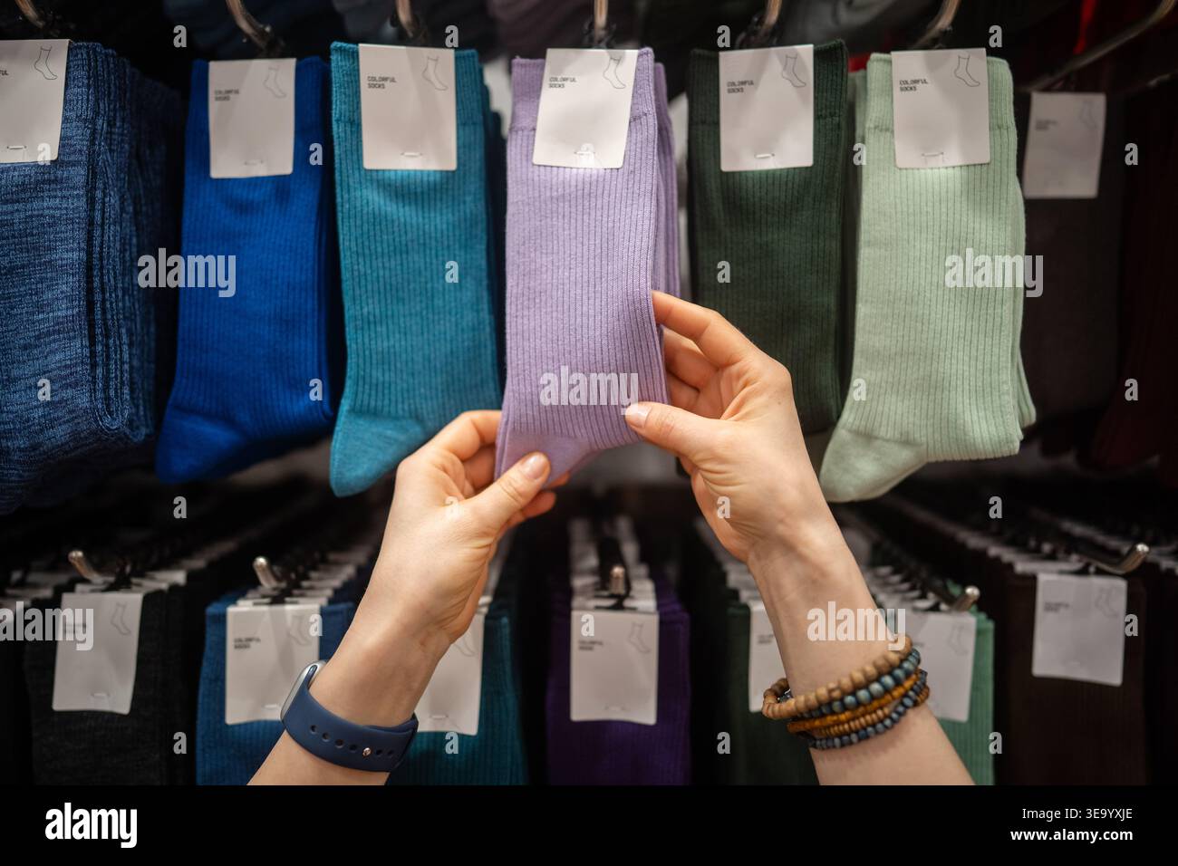 Femme cliente achetant des vêtements au magasin de détail de mode, en choisissant la paire de chaussettes au cintre Banque D'Images