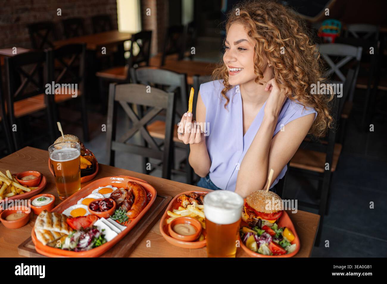 Jeune femme profitant d'un repas savoureux avec de la bière au restaurant Banque D'Images