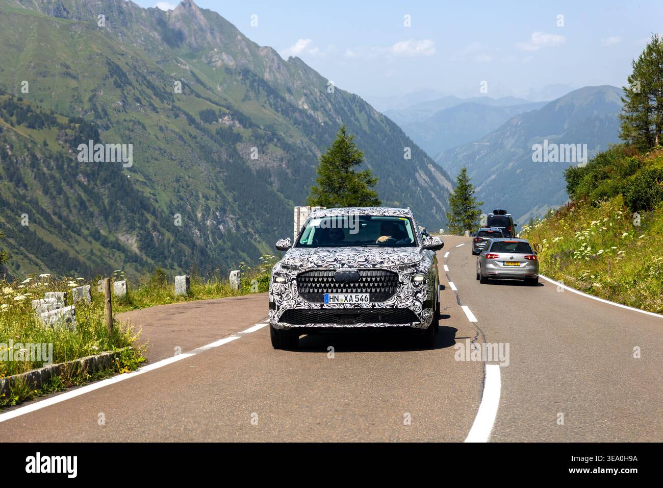 High Alpine Road, Autriche - 31 juillet 2024. Camouflé Audi prototype Drive le long de la route alpine montagnes vertes vallée profonde ciel clair. Pittoresque européenne Banque D'Images