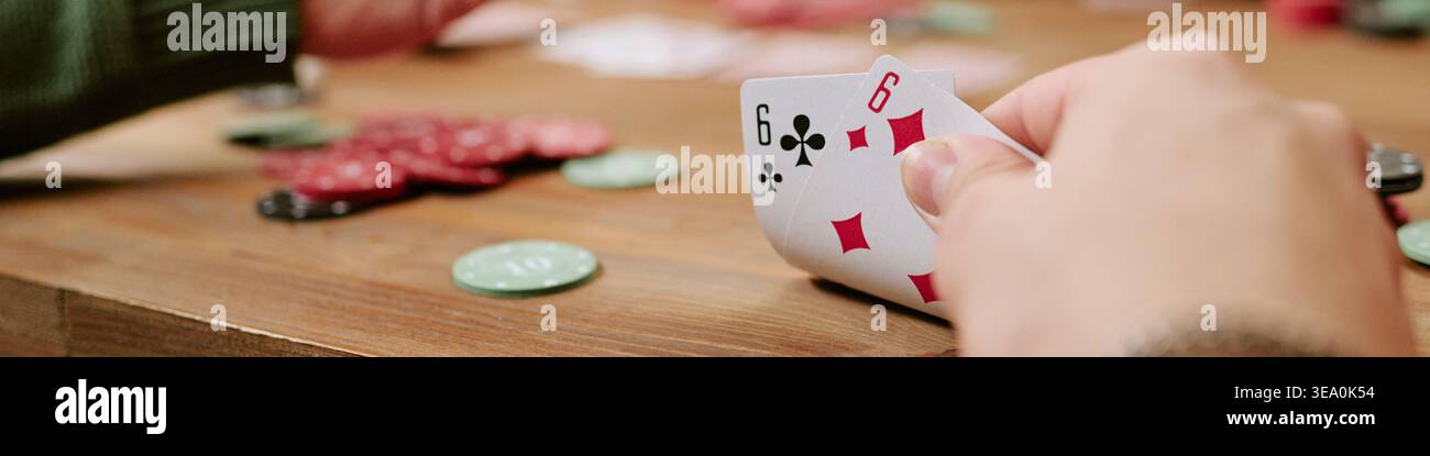En-tête de la main adulte tenant des cartes de jeu pendant la partie de casino Banque D'Images