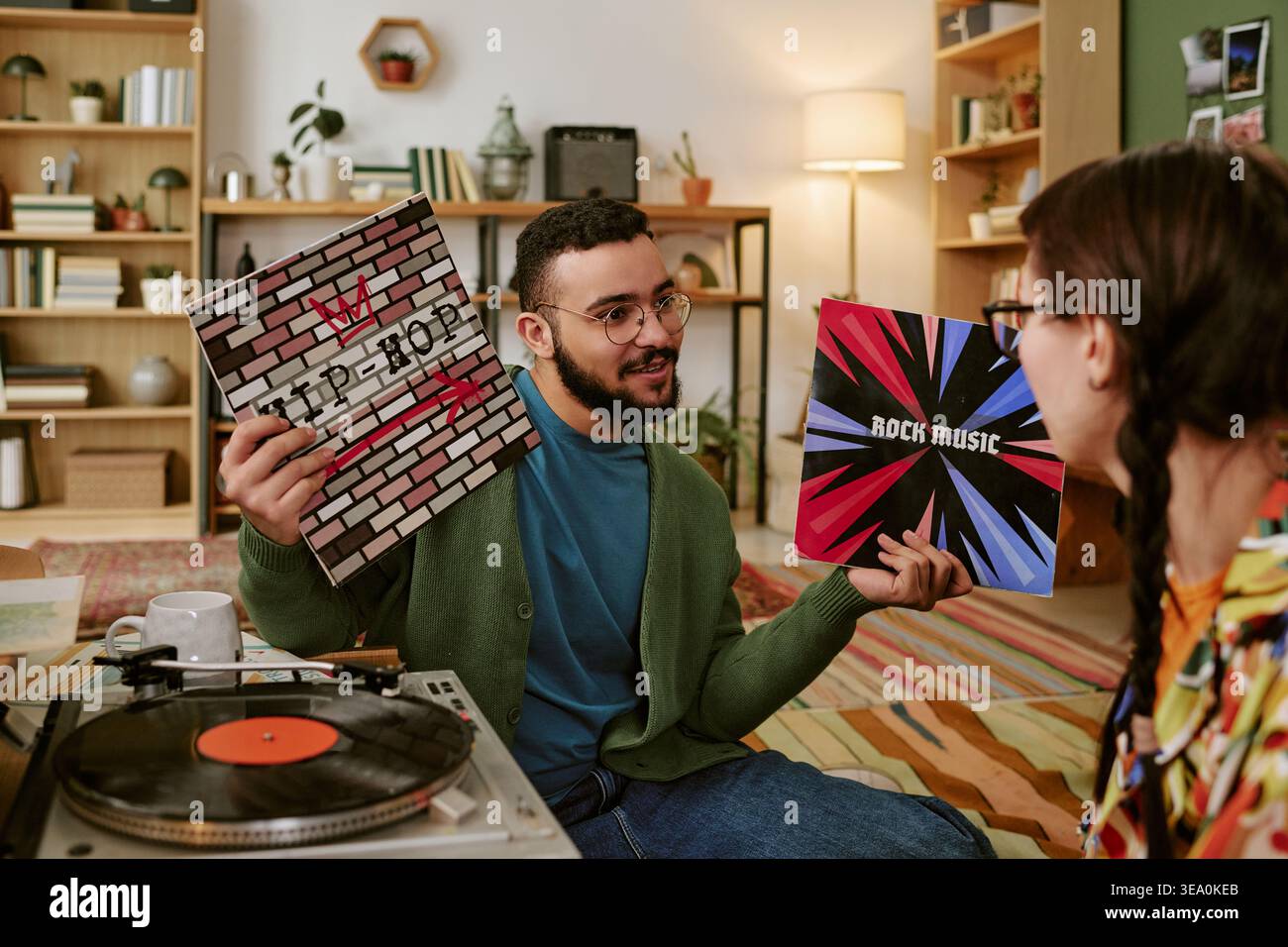 Homme adulte comparant les disques vinyliques pendant l'écoute de musique à la maison Banque D'Images