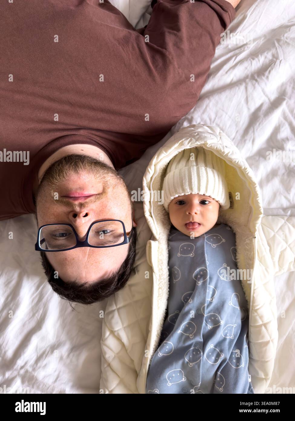 Père et nouveau-né reposant ensemble sur le lit Banque D'Images