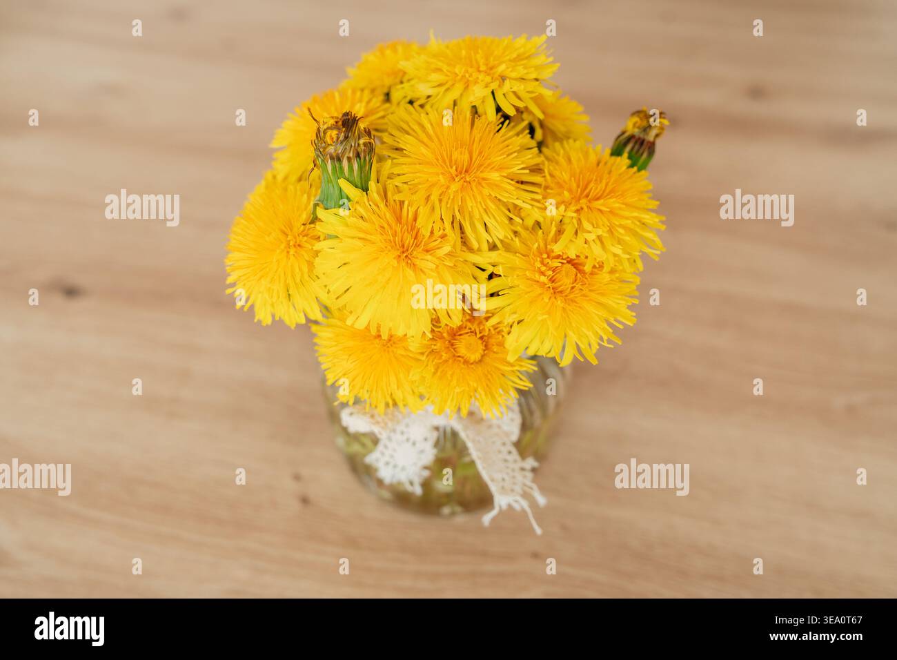 Pissenlits jaunes en verre sur une table en bois. Décor naturel et ambiance printanière. Nettoyer la composition et l'espace de copie. Banque D'Images