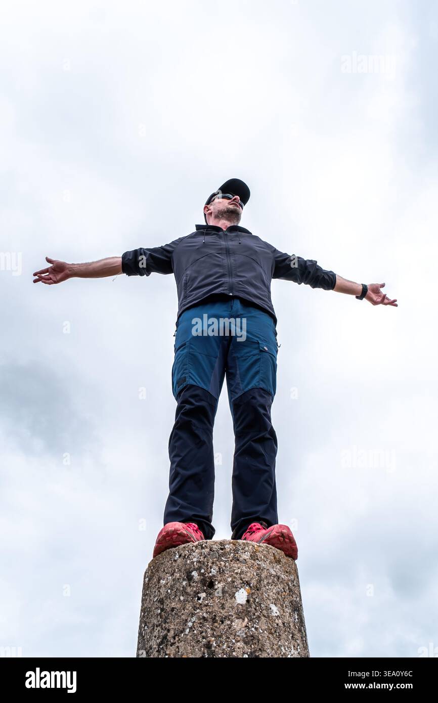 Homme célébrant le succès sur le sommet de la montagne avec les bras larges Banque D'Images