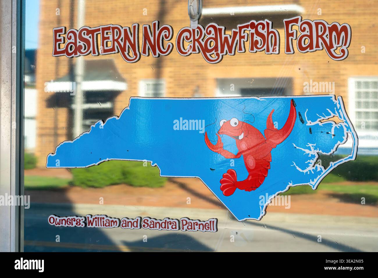 Kenly, Caroline du Nord – signalétique de vitrine pour l'entreprise de fruits de mer Eastern NC Crawfish Farm avec un graphique de carte de Caroline du Nord et une illustration de langouste. Banque D'Images