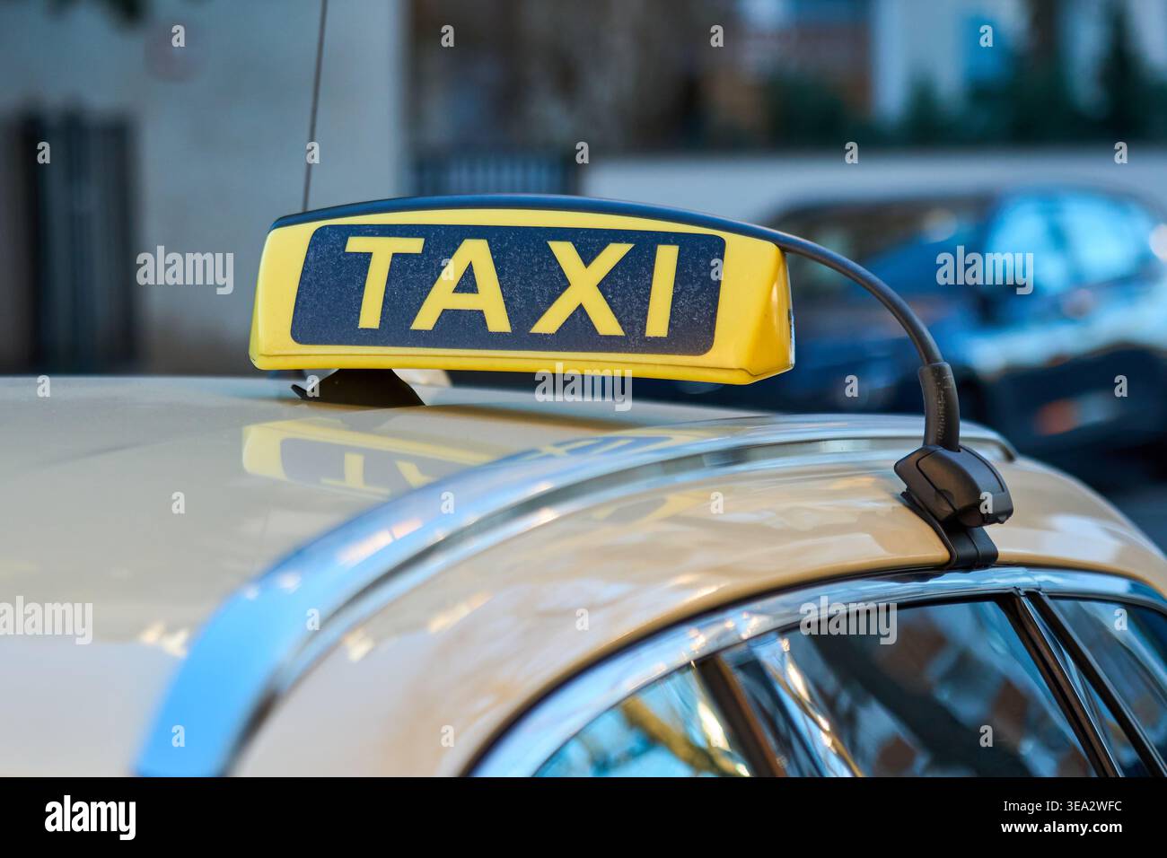 Signe jaune de taxi sur le toit d'une voiture beige dans une rue de la ville. Concept de transport en commun, service de taxi, et transport urbain. Banque D'Images