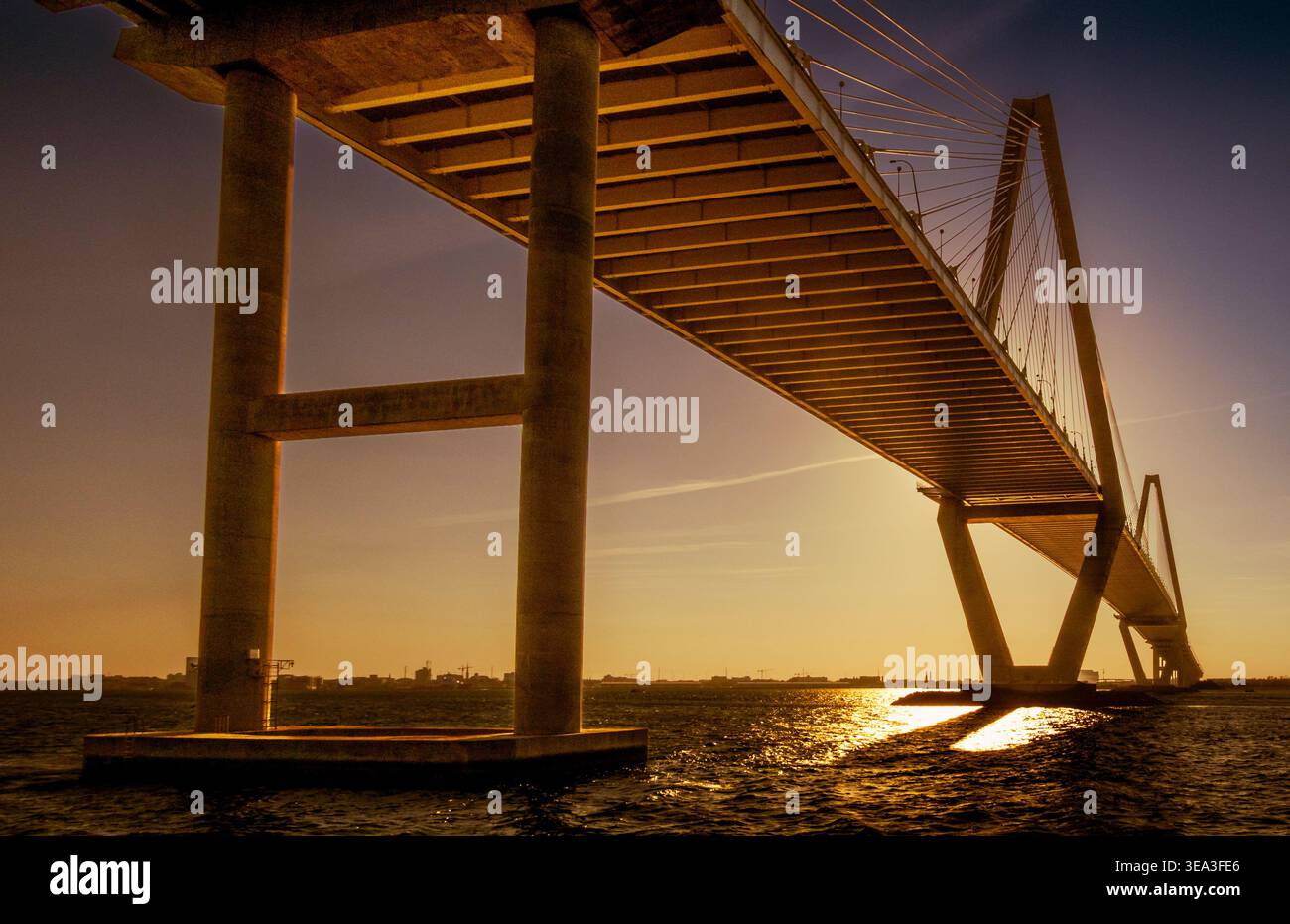Charleston, SC - US - 27 mars 2026 le coucher de soleil doré illumine le dessous de l'Arthur Ravenel Jr. Pont alors que ses supports imposants s'élèvent au-dessus de Rippli Banque D'Images