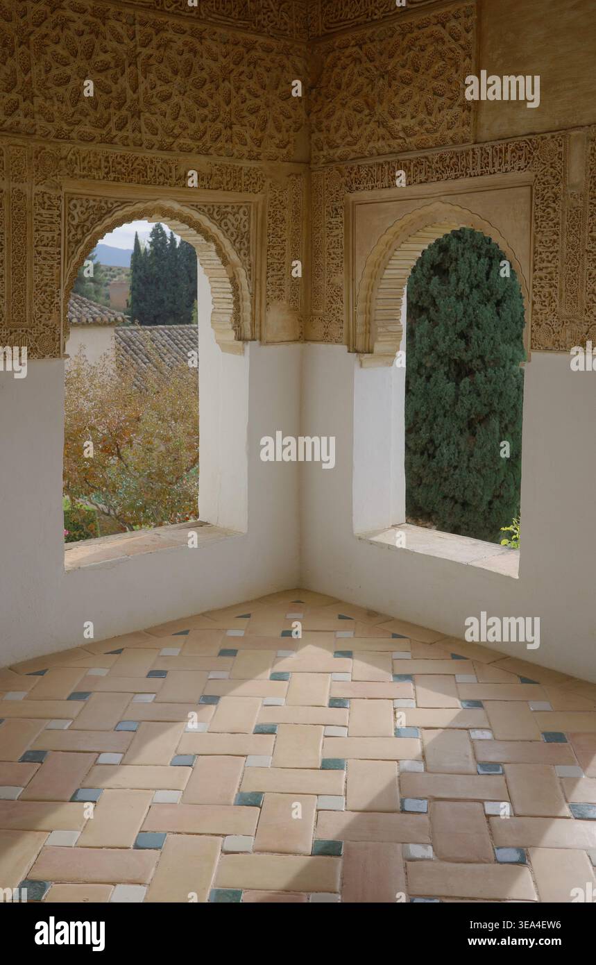 Arches en stuc nasride sculptées avec plâtre arabesque encadrant le jardin vue sur un sol carrelé géométrique dans le palais Generalife, Alhambra, Grenade Banque D'Images
