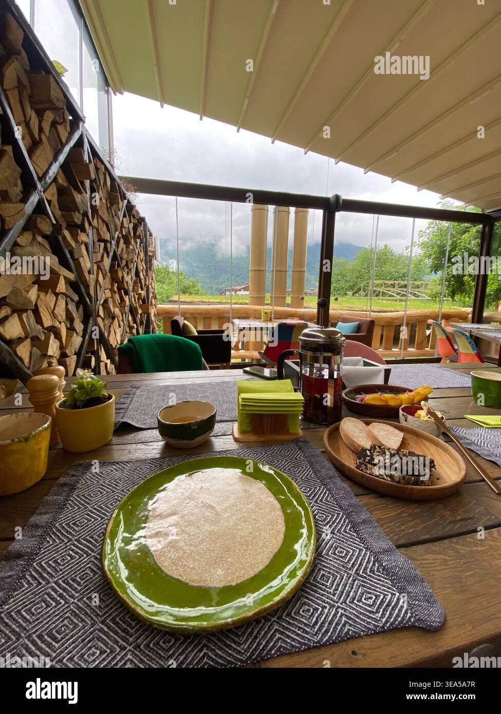 Table de petit déjeuner avec pain et thé sur terrasse confortable avec vue sur la montagne et ciel nuageux - Image de stock capturée avec un smartphone