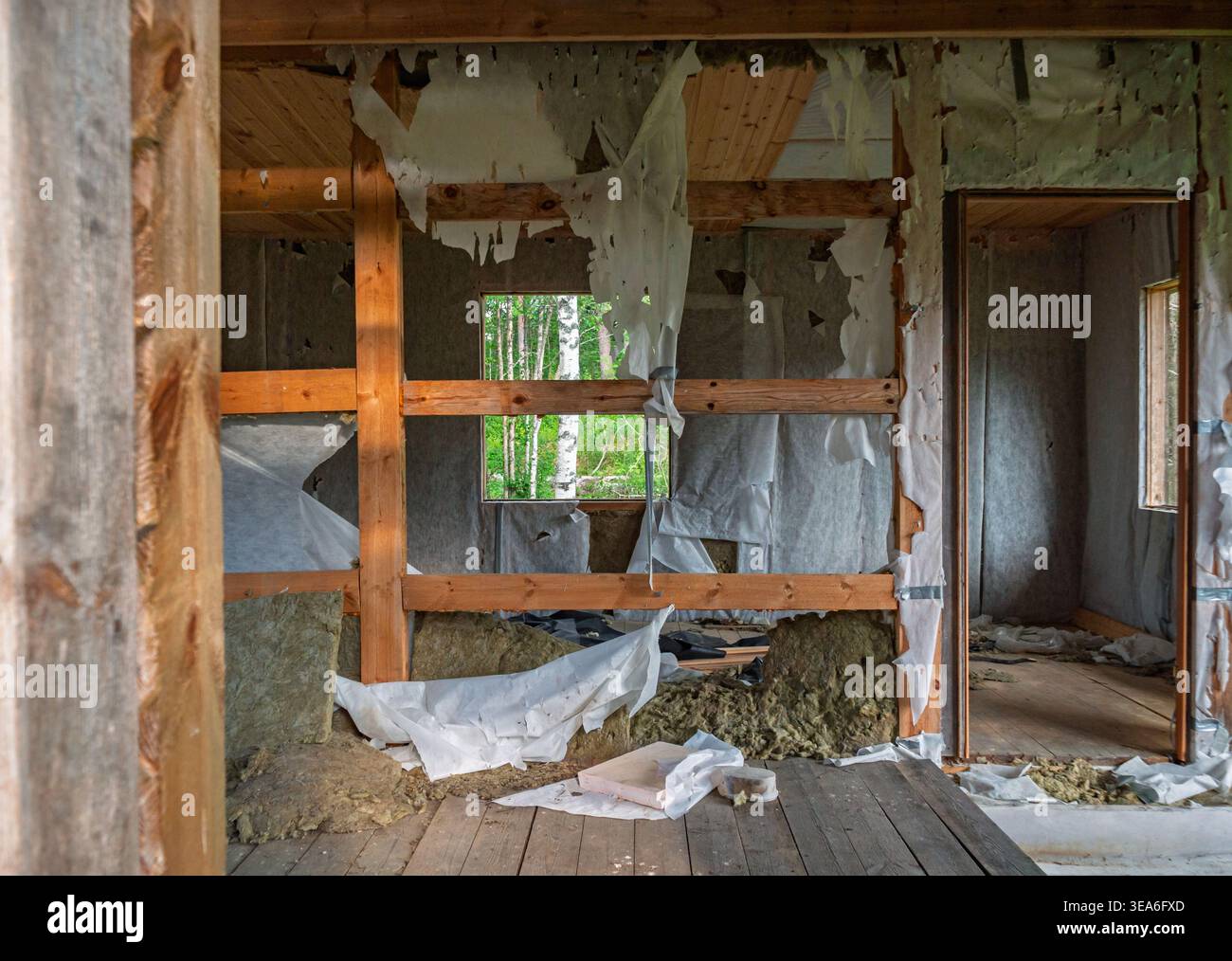 Vue intérieure d'une maison abandonnée avec poutres apparentes en bois et matériaux d'isolation murale déchirés pendant la journée Banque D'Images