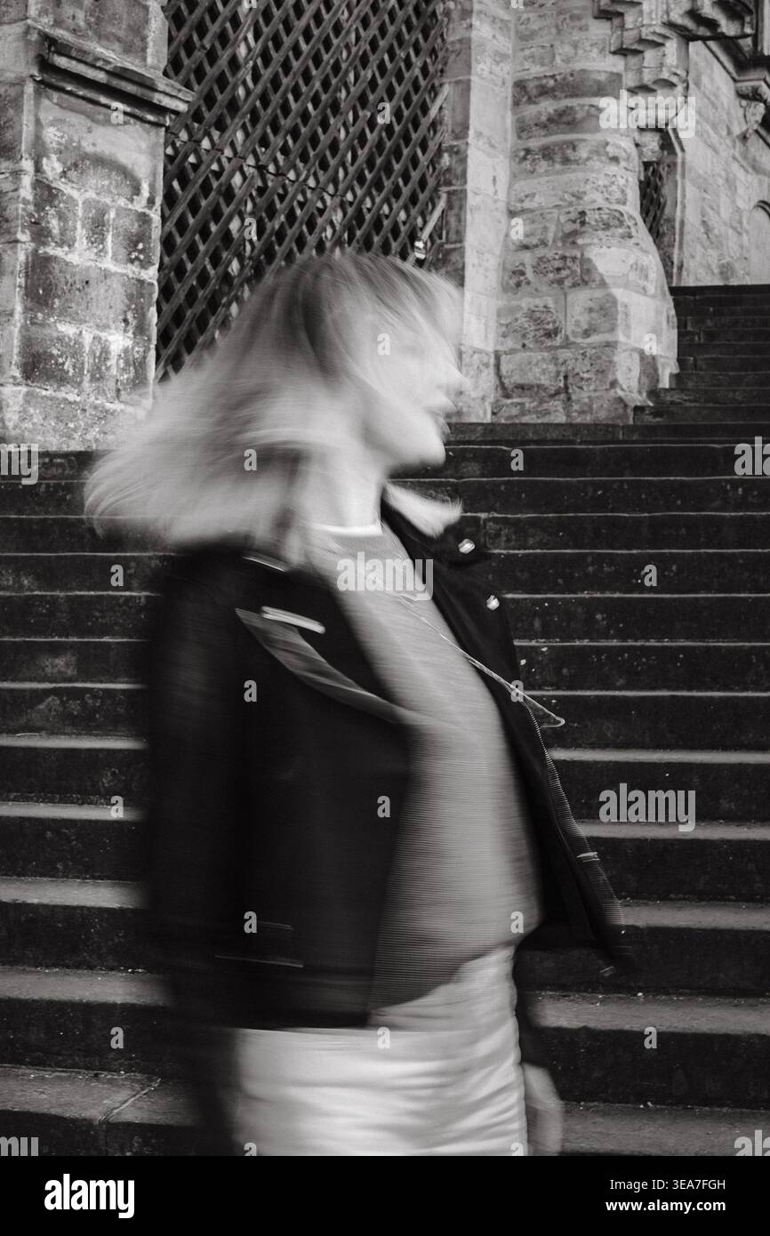 Portrait artistique en noir et blanc d'une femme floue sur des escaliers de pierre près de l'architecture historique de la cathédrale. Image urbaine conceptuelle avec mouvement, anonymi Banque D'Images