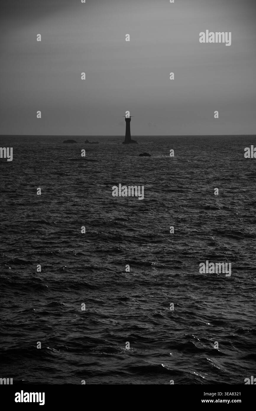 Paysage marin minimaliste noir et blanc avec phare lointain et horizon calme. Banque D'Images