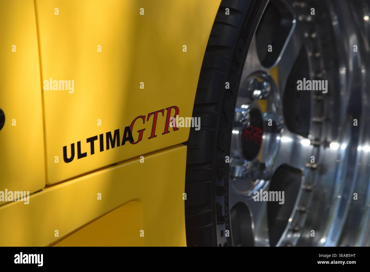 Gros plan d'une voiture Ultima GTR jaune montrant l'autocollant de carrosserie Ultima GTR et une jante en alliage à rayons multiples polie lors d'un salon automobile en plein air. Banque D'Images