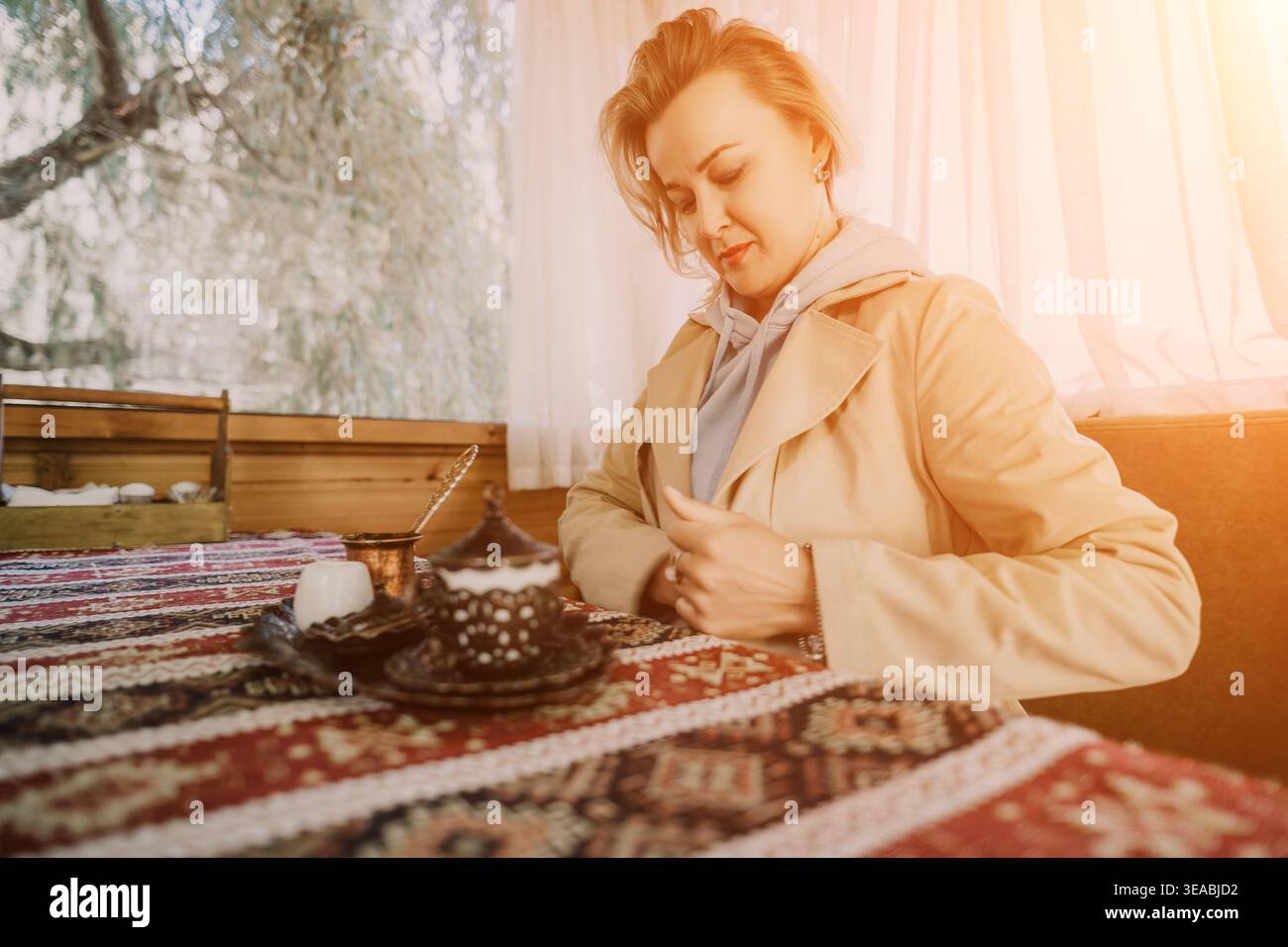 Woman Writing Coffee Shop Notebook - Une jeune femme écrit dans un cahier tout en profitant d'une tasse de café dans un café. Banque D'Images