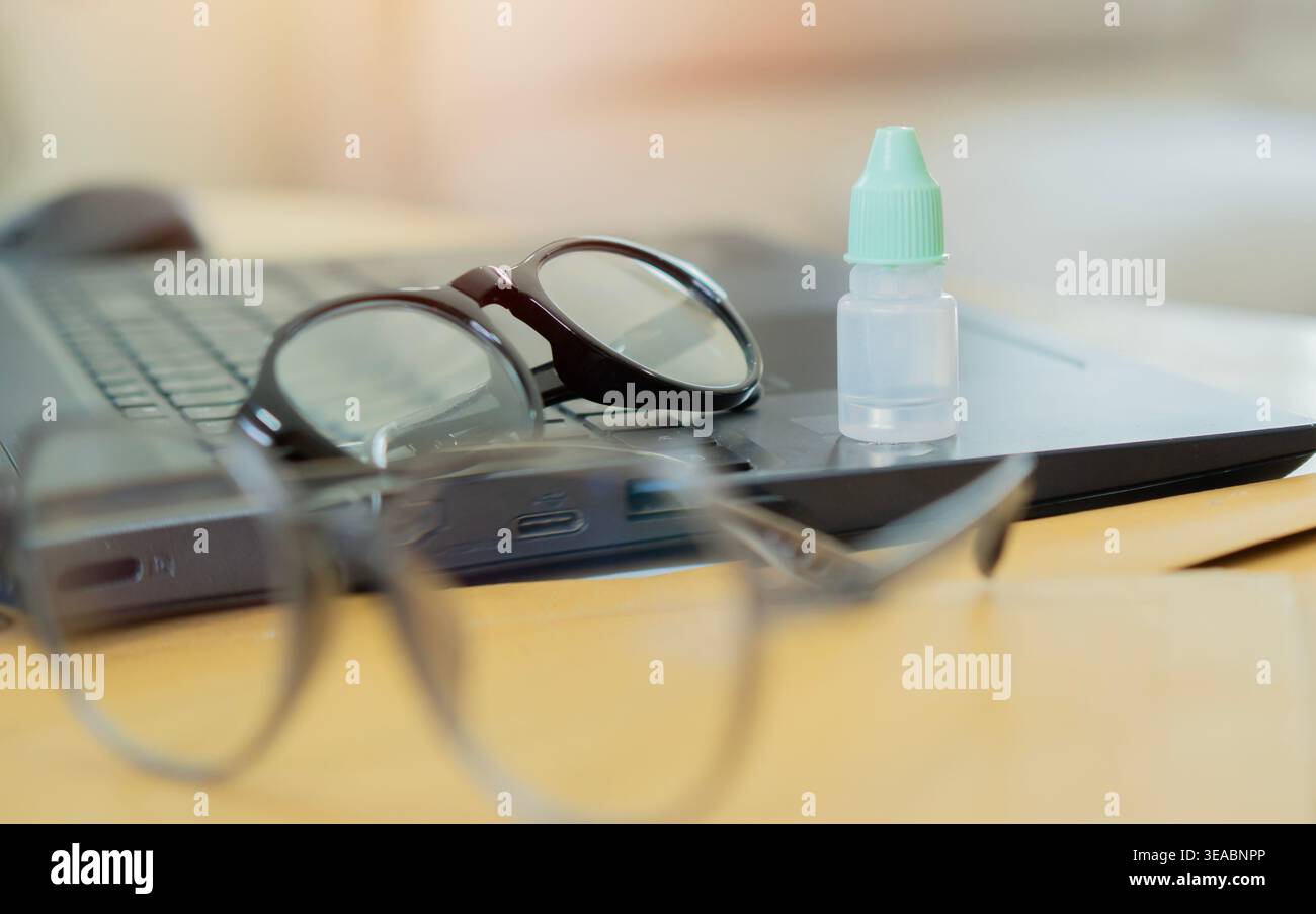Gouttes oculaires et lunettes sur ordinateur portable au lieu de travail. Traitement et prévention des maladies oculaires. Mise au point sélective. Banque D'Images