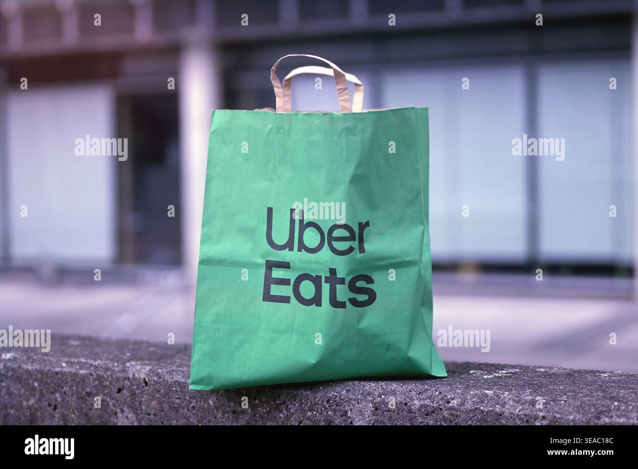 Ulm, Allemagne - 16 avril 2026 : Uber mange livraison sac en papier avec de la nourriture debout à l'extérieur. Banque D'Images