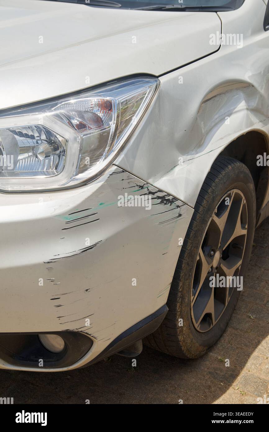 pare-chocs avant endommagé et garde-boue de voiture blanche, bosses et marques de rayures noires sur la carrosserie, l'assurance accident de voiture ou le concept de réparation de véhicule en soft focus Banque D'Images
