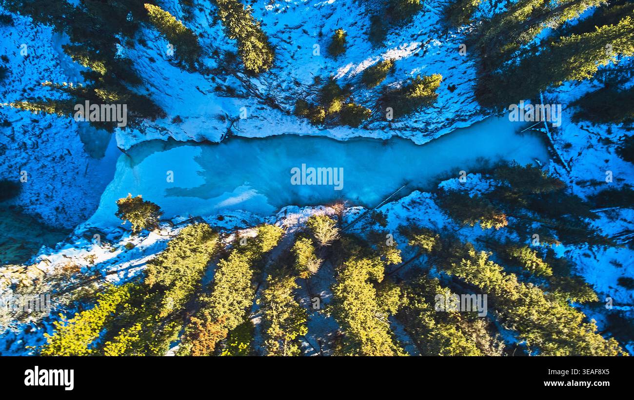 Chute d'eau glacée aérienne et forêt de pins enneigés en hiver Banque D'Images