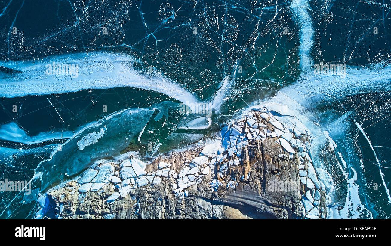 Fissures aériennes de glace du lac gelé et scène hivernale de Rocky Shoreline Top Down Banque D'Images