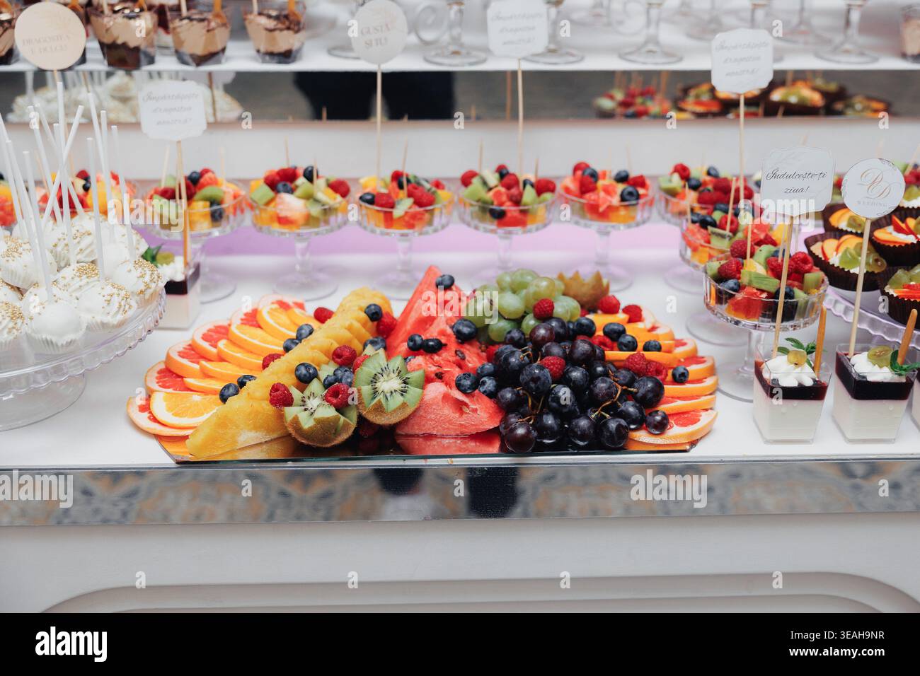 Plateau de fruits coloré et présentoir de desserts avec tranches d'agrumes, de baies et de brochettes tropicales disposées sur le comptoir de marbre, vif été pour le brunch Banque D'Images