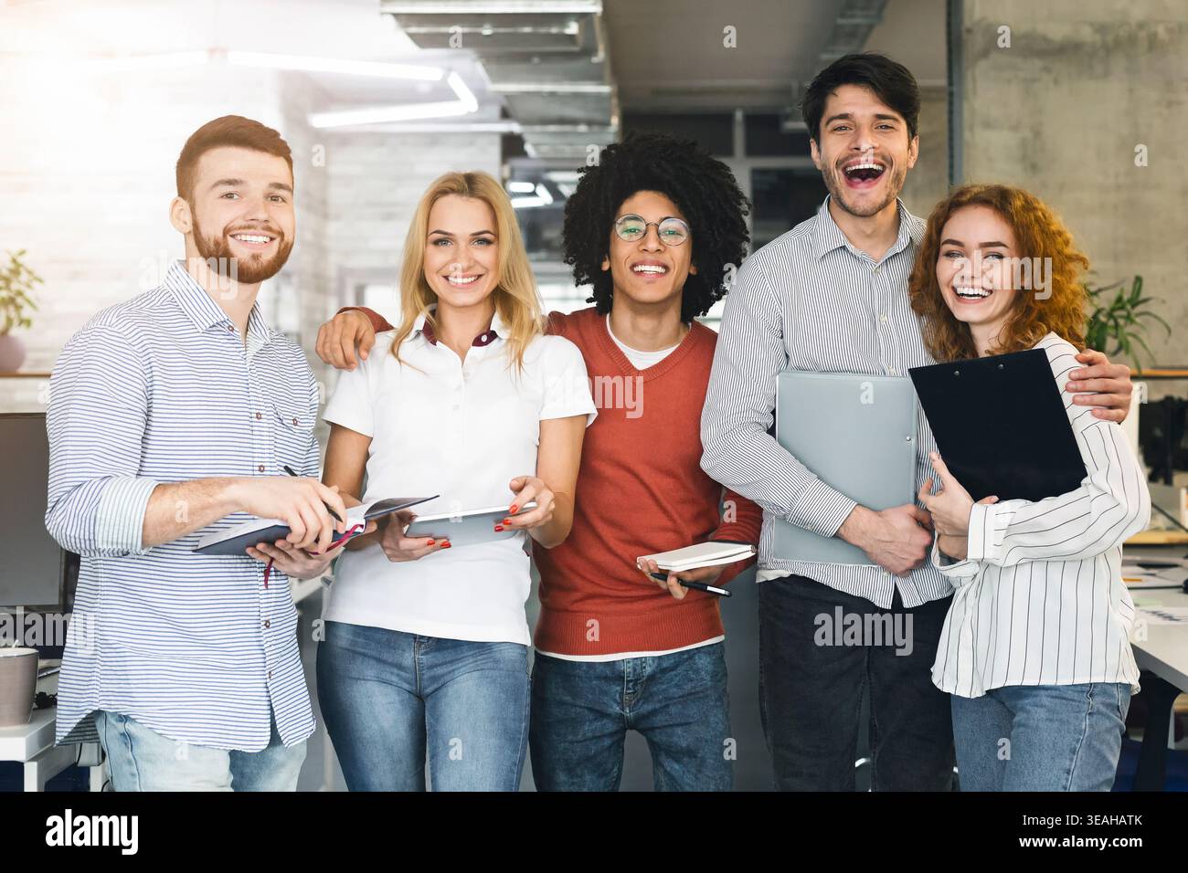 Groupe de jeunes professionnels souriant ensemble dans un environnement de bureau moderne pendant la journée Banque D'Images