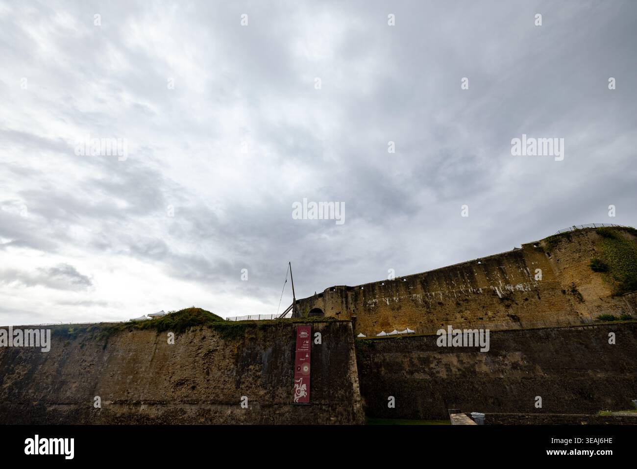 Château de Sedan, Sedan, Rethel, Ardennes, Grand-est, France, 28 août 2025, rempart altéré contre scène de ciel sombre, vue panoramique d'en bas du mur défensif en pierre historique avec nuage couvant Banque D'Images