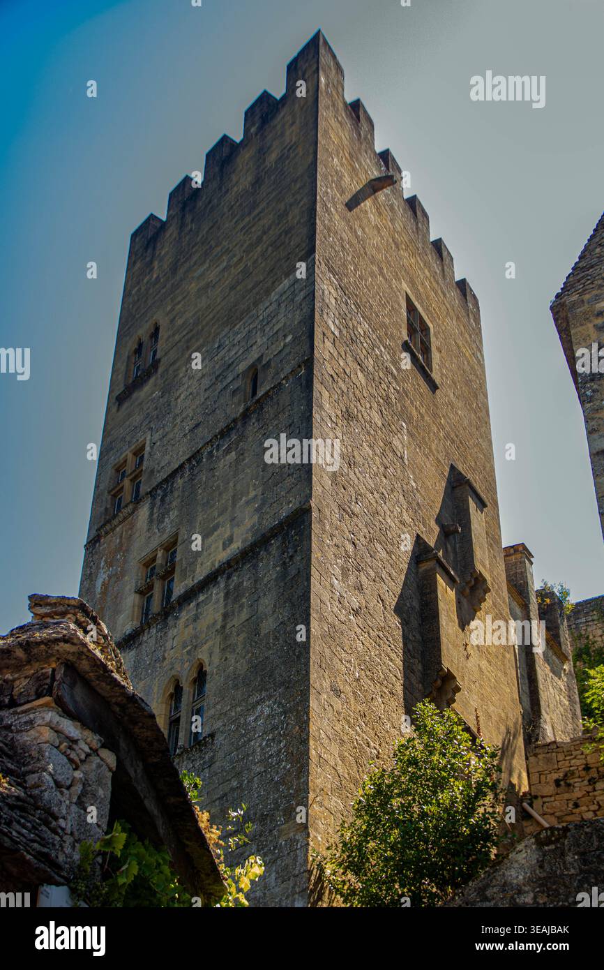 Une vue éditoriale détaillée sous angle bas de la tour défensive massive en pierre du Château de Beynac. L'image met en valeur l'arc historique en calcaire doré Banque D'Images