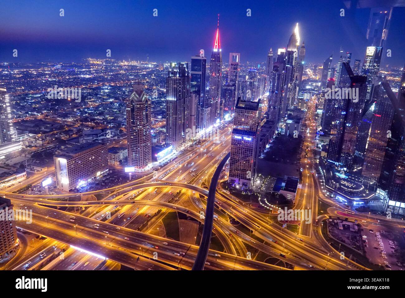 Vue aérienne de la ligne d'horizon illuminée de Dubaï la nuit avec le trafic de Sheikh Zayed Road et les gratte-ciel incandescents sous un ciel crépusculaire bleu profond Dubaï, Banque D'Images