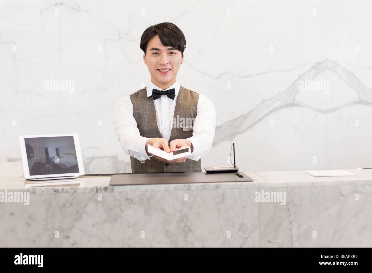 Une réceptionniste de l'hôtel remet une carte-clé à un client à la réception. Banque D'Images