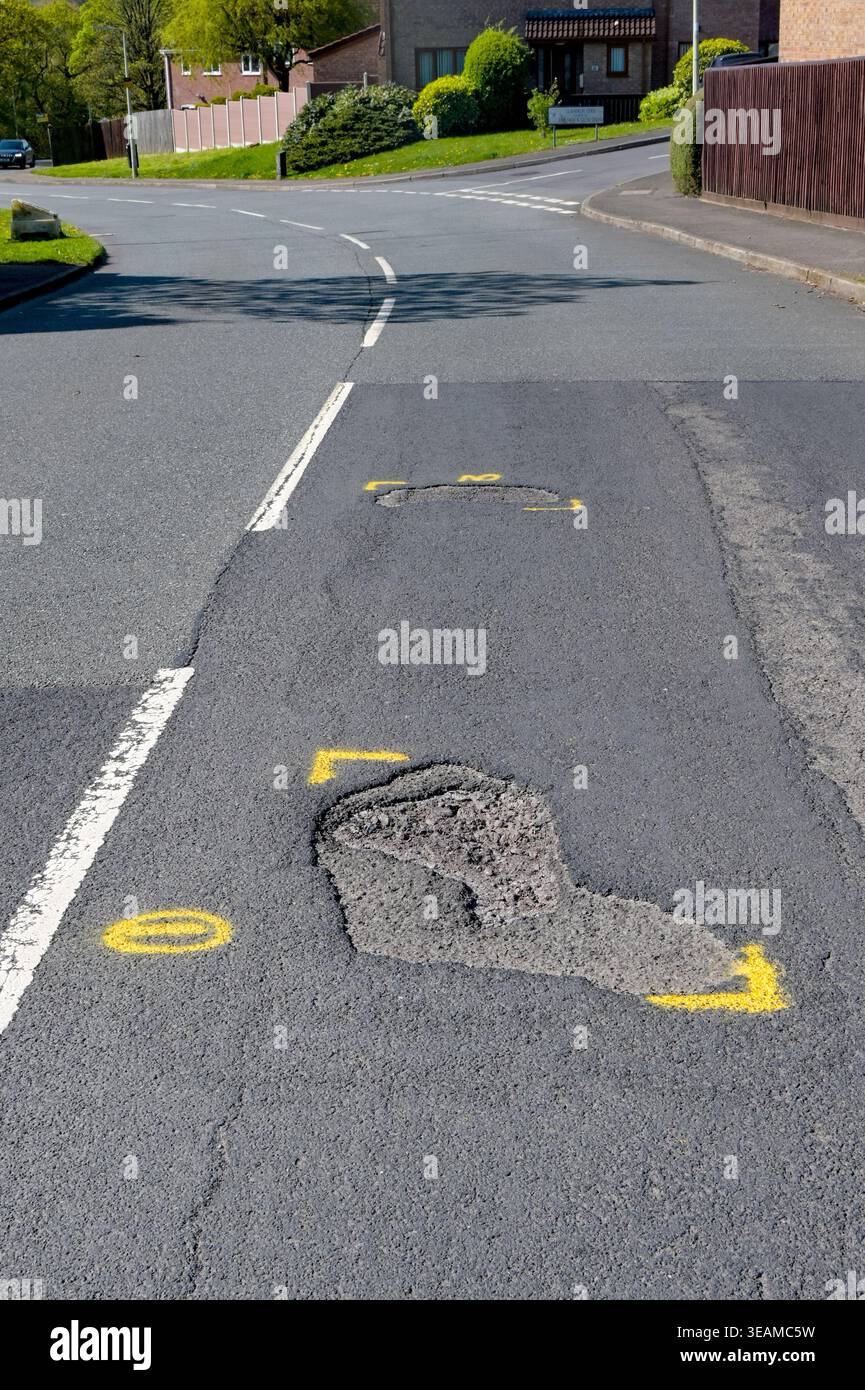 Pontypridd, Rhondda Cynon TAF, pays de Galles - 22 avril 2026 : nids de poule sur une route principale traversant une zone résidentielle délimitée par de la peinture jaune pour réparation. Banque D'Images