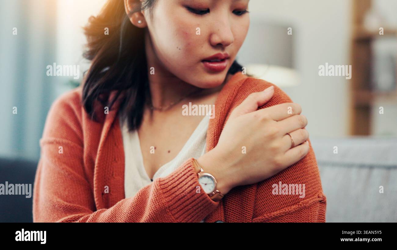 Épaule, douleur et femme asiatique sur canapé avec blessure pour fibromyalgie, ostéoporose et inflammation. Bras de massage de la maison, bouleversé et de la personne pour la fatigue Banque D'Images