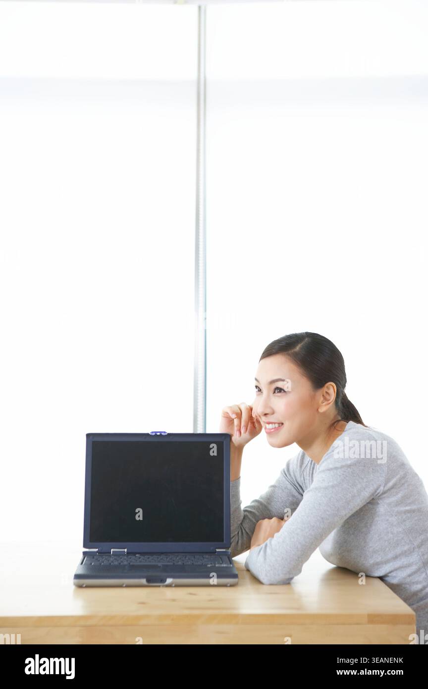 Une femme est assise devant un ordinateur portable avec un écran vide. Banque D'Images